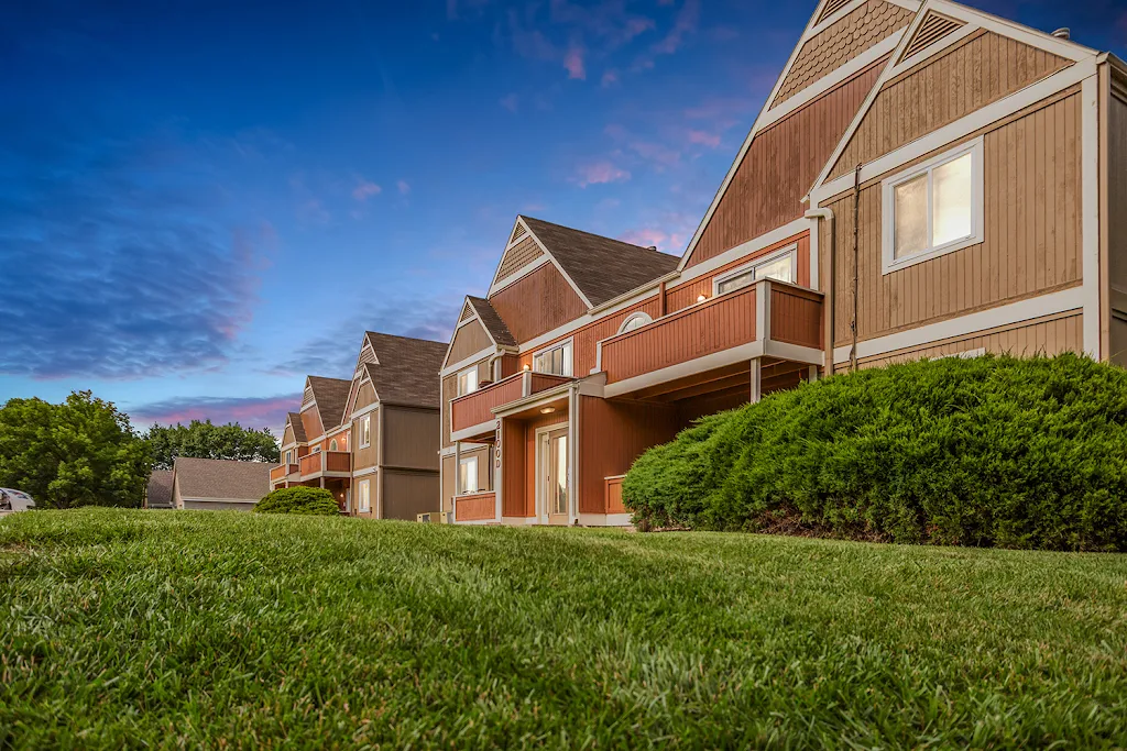 Exterior or apartment building with landscaping at dusk 