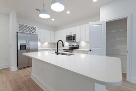 Kitchen with large island, white cabinets, stainless steel appliances, and black hardware