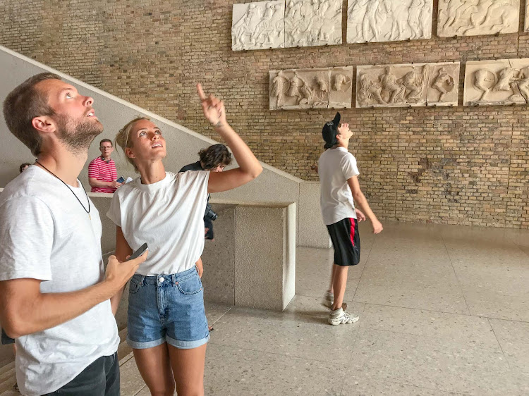 Visitors to the Neues Museum admire reliefs on the ceiling and walls.