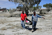 Two residents of Jagersfontein carry a suitcase of clothes they saved after the mudslide destroyed homes. 