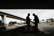 Clement Nocanda, left, and Thabang Mokoena gather possessions as they prepare to leave their home, the M2 bridge, to go and 