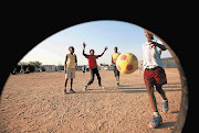 SMALL CHANGE: Children play football on a dusty field in Diepsloot, Johannesburg, in the absence of a proper soccer field. Details of how millions of rands in World Cup development money were spent on luxury cars were uncovered by the Sunday Times this week Picture: SIMPHIWE NKWALI