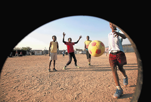 SMALL CHANGE: Children play football on a dusty field in Diepsloot, Johannesburg, in the absence of a proper soccer field. Details of how millions of rands in World Cup development money were spent on luxury cars were uncovered by the Sunday Times this week Picture: SIMPHIWE NKWALI