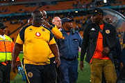 Kaizer Chiefs coach Molefi Ntseki is escorted off the field by police as fans throw missiles at him during the Carling Knockout Cup match against AmaZulu at FNB Stadium on Saturday night. 