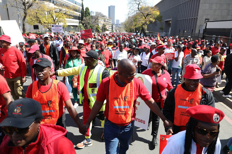 Cosatu and Saftu members hold hands during a protest action.