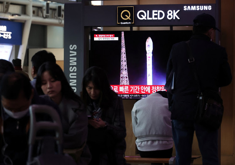 People sit by a TV broadcasting a news report on North Korea launching a military satellite, at a railway station in Seoul, South Korea, on November 22 2023. Picture: KIM HONG-JI/REUTERS