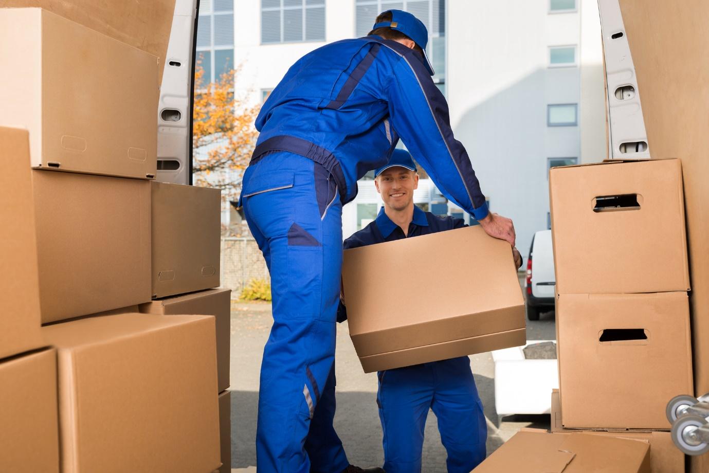 two men in uniform unloading boxes from an interstate moving van