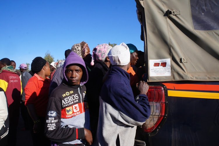 Nduma village residents watch the body of the suspect in the police car.