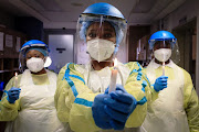 A nurse at Netcare Sunninghill Hospital's emergency department, Nothile Ngubeni, with colleagues Dorcus Sithole, left, and Jones Dick, hold candles in honour of those who lost their lives to Covid-19. File image.