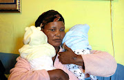 Nombuso Mbilini with the twin babies of her son Mzimasi, 27, who was shot dead at a spaza shop in Khayelitsha last month. He was among 13 victims who died from gunshot wounds that weekend.   