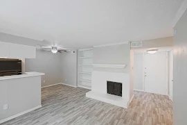 Open living and dining room area with access to the kitchen. White painted brick fireplace with a built in bookshelf next to it.