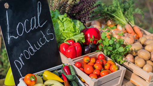 Counter with fresh vegetables and a sign of local products stock photo