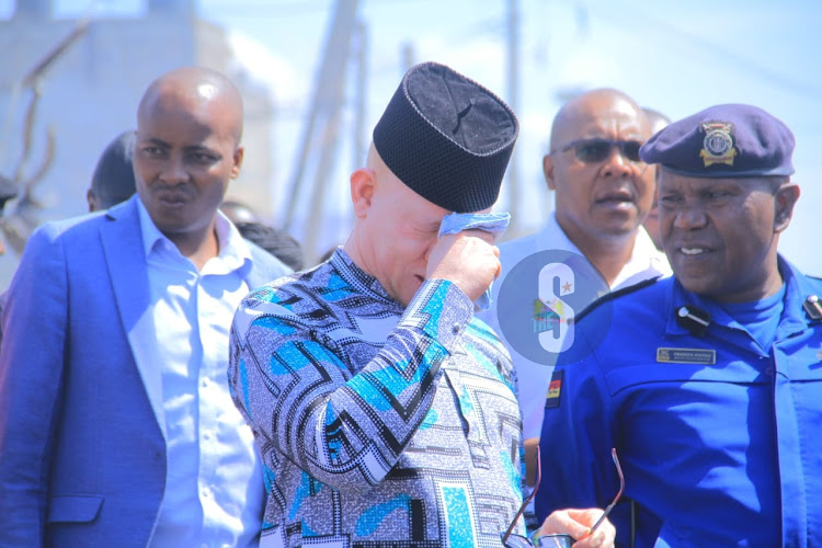 Government Spokesperson Isaac Mwaura wiping his eyes as he assess the scene of the Embakasi fire tragedy in Nairobi on February 2, 2024