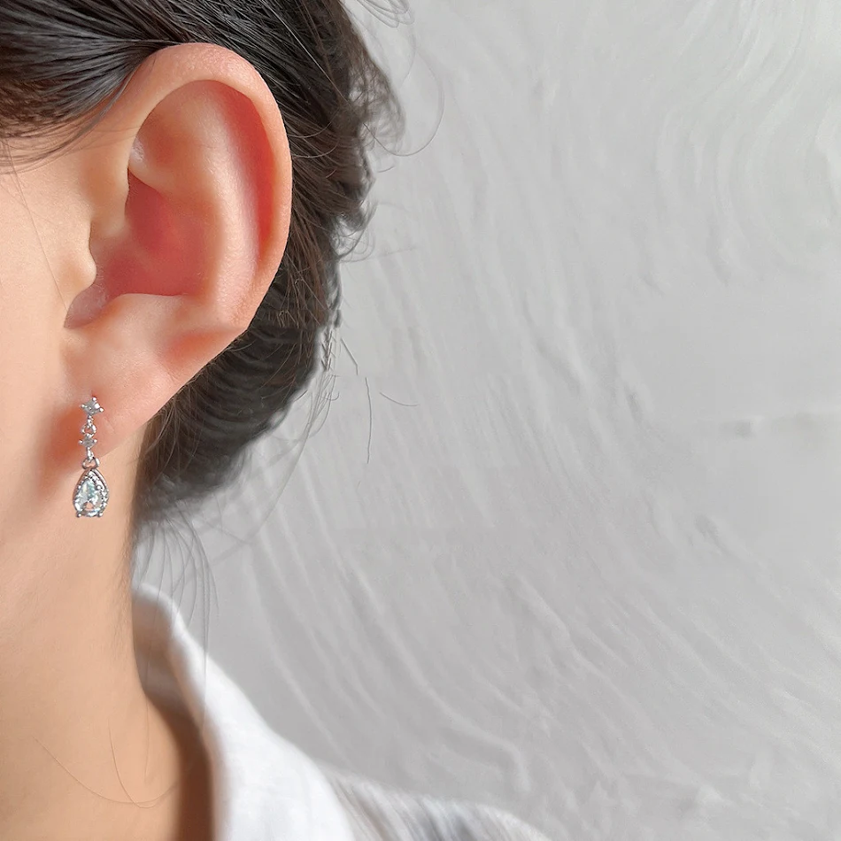 Clous d'oreilles en argent avec micro-incrustations de zircon, aiguille fine, forme de larme bleu clair, élégance et raffinement.