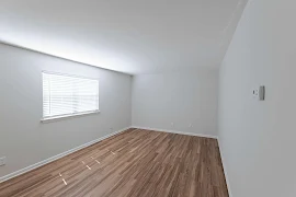 Living room with wood-inspired flooring, gray walls, white trim, and a window with blinds