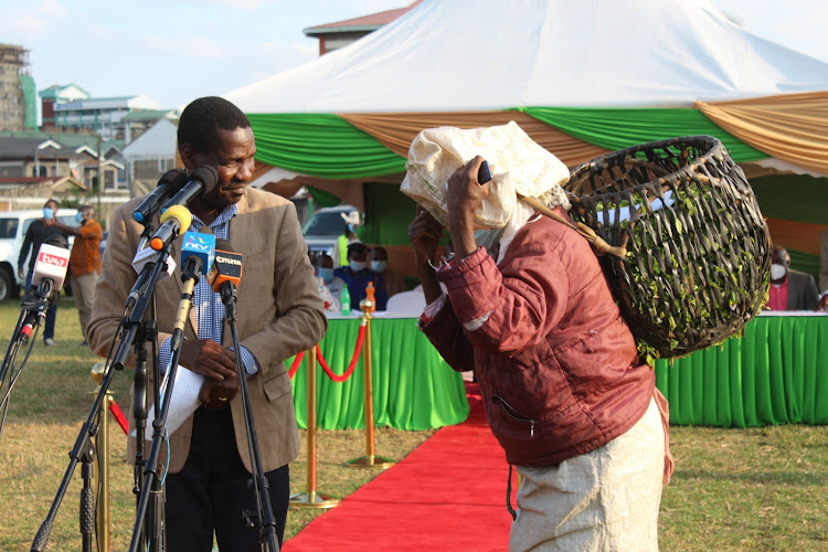 Agriculture CS Peter Munya with a farmer during a meeting on tea regulations at Othaya stadium in Nyeri on Friday.