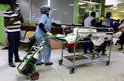 An unknown medical worker wheels a patient towards the consultation cubicle at the emergency section of the Kenyatta National Hospital during a doctors' strike, amid the spread of the coronavirus disease (COVID-19), in Nairobi, Kenya December 21, 2020.