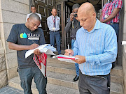 Lawrence Mbalati programme manager at Heala  hands a petition to treasury's chief of staff Marlon Geswint. 