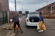 A 34-year-old Uber driver helps a commuter get her groceries out of the boot in Atteridgeville.