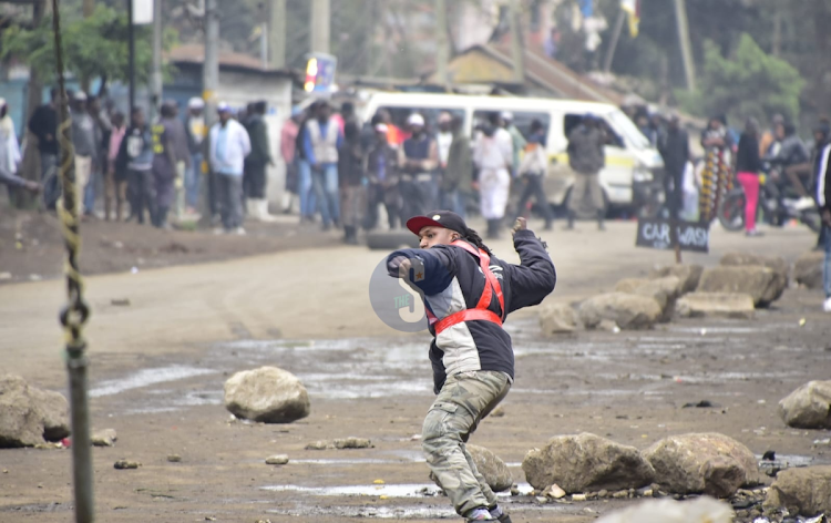 A man throwing back a teargas canister to police officers on July 7,2023.