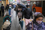 Pedestrians wearing face masks walk on the street following the outbreak of the coronavirus disease (Covid-19) in Hong Kong, China February 19, 2022. 