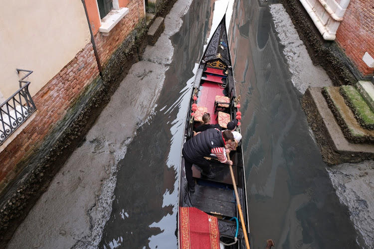 A gondola is pictured in a canal during a severe low tide in the lagoon city of Venice, Italy, March 17, 2022.