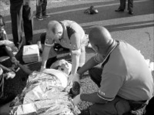 VICTIM: Paramedics stabilise a woman who was hit by a crar on a busy freeway in KwaZulu-Natal. 19/07/07. © Sowetan.