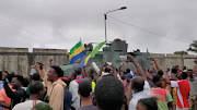 A military vehicle passes people celebrating in Port Gentil, Gabon, on  August 30 2023 after military officers announced they had taken power after the state election body announced President Ali Bongo had won a third term. This still image was obtained from a social media video. 
