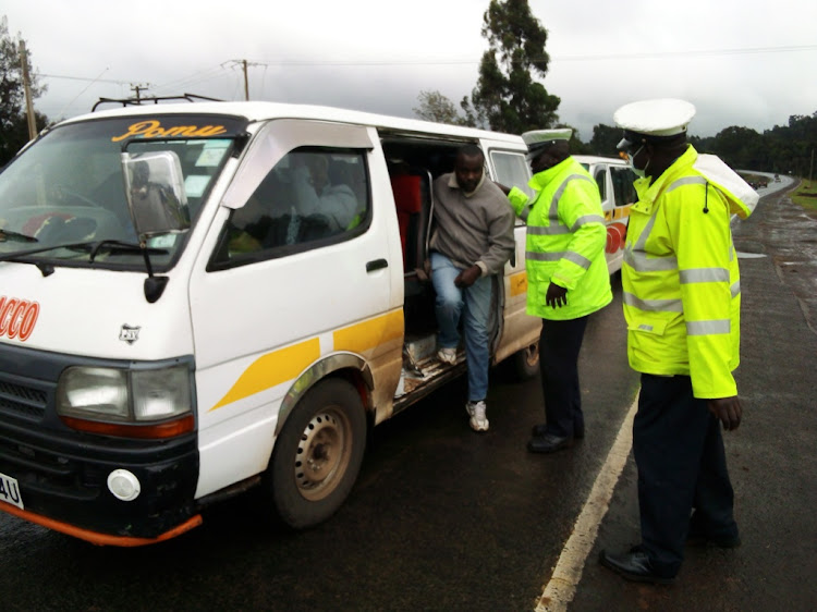 FILE: Traffic police officers inspect vehicles at Manguo area along the Nairobi-Nakuru highway on Tuesday, December 21.