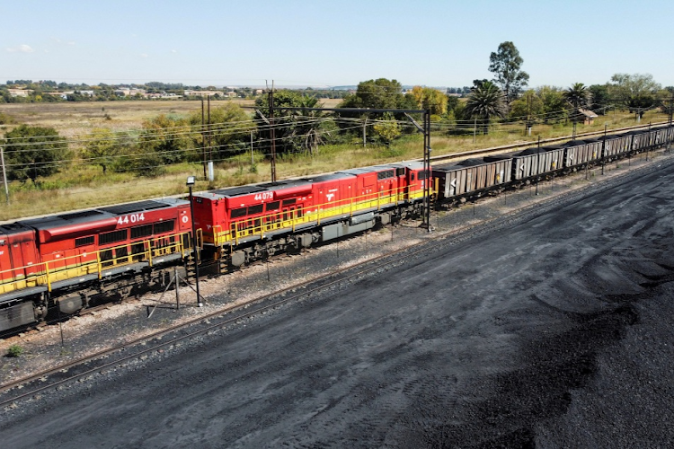 A Transnet Freight Rail train is seen next to tons of coal mined from the nearby Khanye Colliery mine, at the Bronkhorstspruit station, in Bronkhorstspruit.