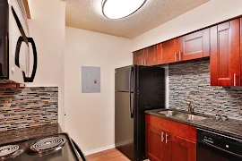 Kitchen featuring title backsplash, black appliances, wood cabinets, and overhead lighting. 