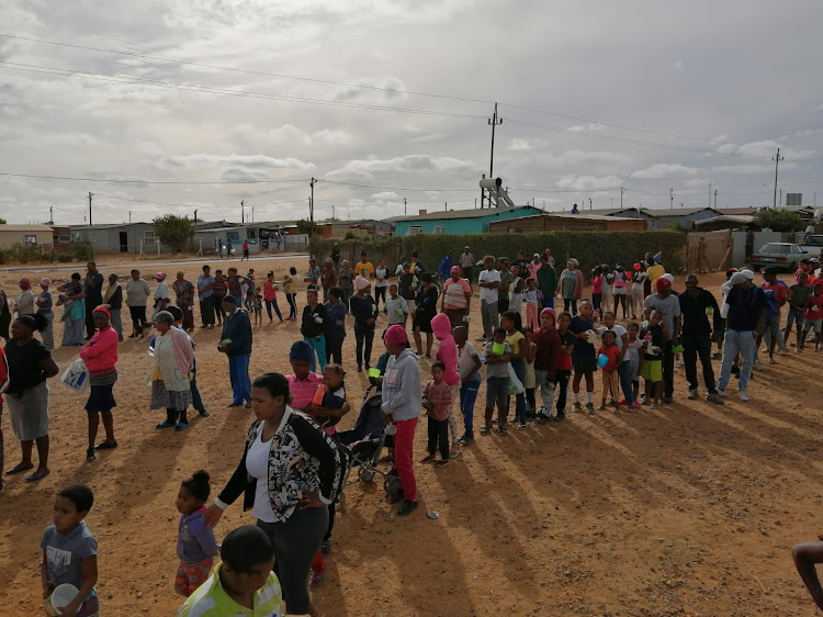 Hundreds of residents stand in several queues and wait for the arrival of volunteers to arrive with food at 3 pm each day. The people are orderly and patient. There is more than enough to go around.