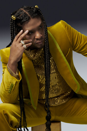 Law Roach is sitting down in a yellow suit and statement rings.