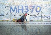 HOPEFUL: A woman writes a message on a display at Kuala Lumpur Airport days after the disappearance of Malaysia Airlines flight MH370. File photo