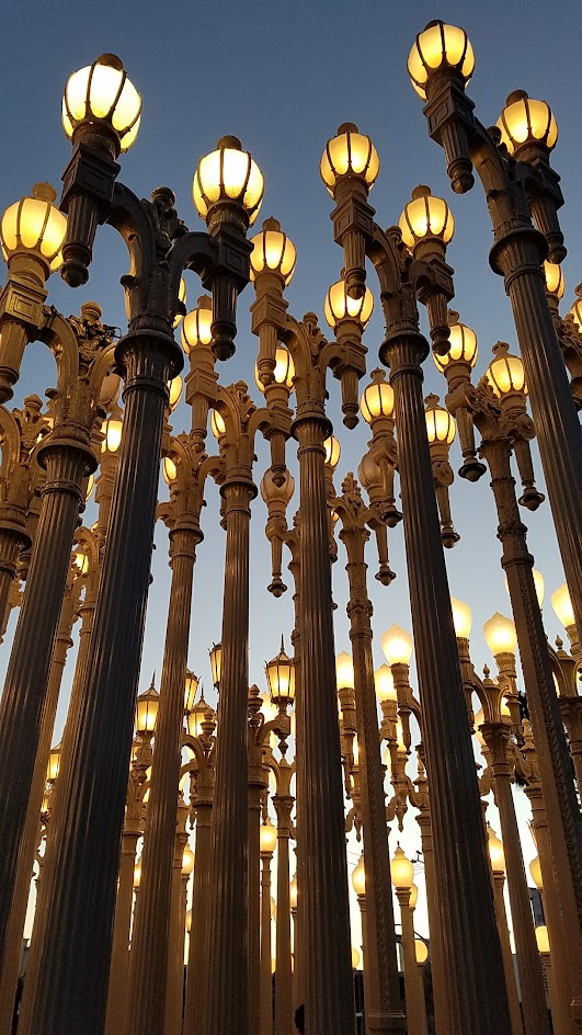 One of the most famous and free (since it is an outdoor sculpture) art you can see in the park at LACMA is the iconic Urban Lights. Created by Chris Burden, it is made of 202 restored street lamps in various styles based on where they were from (most are from southern California and some from Portland Oregon too!). The lamps are painted grey and assembled in a grid, and are solar powered and become lit in the evening.