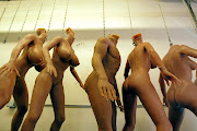 Unfinished silicone RealDoll sex dolls hang from chains in the factory. 