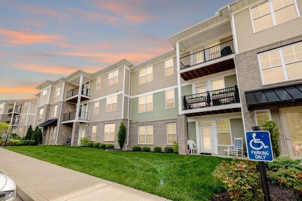 Modern apartment complex with balconies at dusk, handicap parking sign visible.