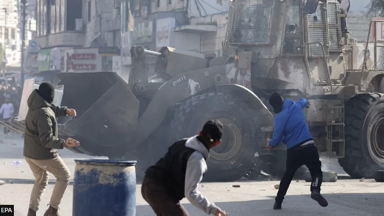 Palestinians throw stones amid clashes with Israeli troops during a raid in Jenin.