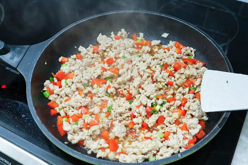 Adding Peppers, Water Chestnuts, Scallions, And Chili Pepper Flakes, And Seasoning Mixture.