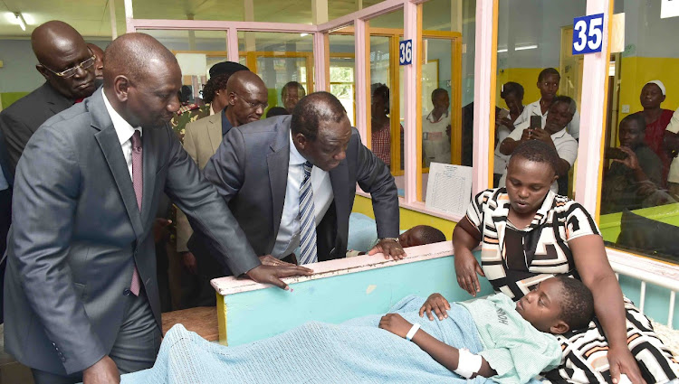 Deputy President William Ruto, Education CS George Magoha, and Kakamega Governor Wycliffe Oparanya with a survivor of Kakamega Primary School stampede with a parent at Kakamega Referral Hospital.