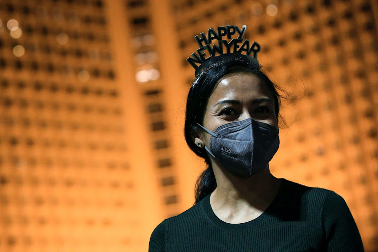 A woman wearing a protective face mask and a headband looks on at the Bundaran Hotel Indonesia roundabout, where people usually celebrate on New Year's Eve, in Jakarta, Indonesia, on December 31 2021.