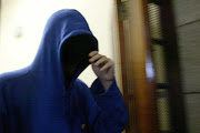 Sizzlers murder accused Adam Woest covers his face with his hood as he leaves the high court in Cape Town during a court appearance in March 2004. Archive photo.