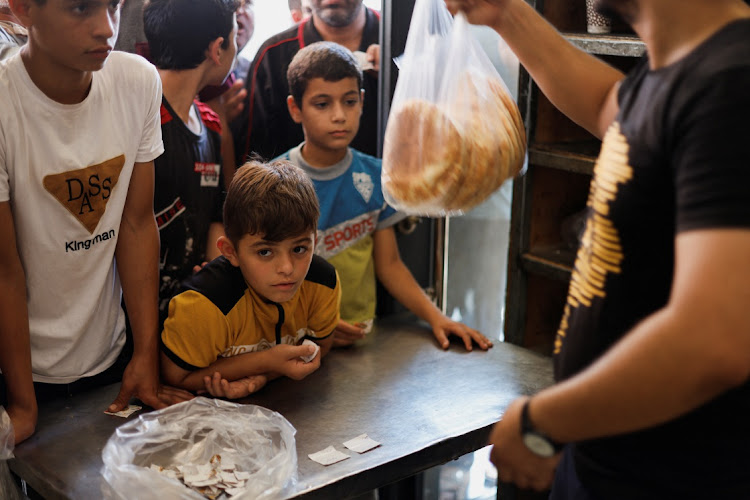 Palestinians wait to buy bread outside a bakery, amid the ongoing conflict between Israel and Palestinian Islamist group Hamas, in Khan Younis in the southern Gaza Strip October 14, 2023.