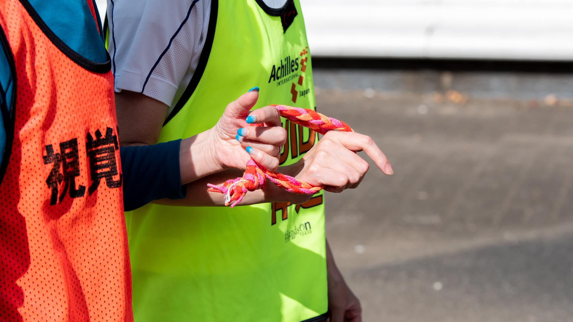 Two runners holding a pink colored tether rope.