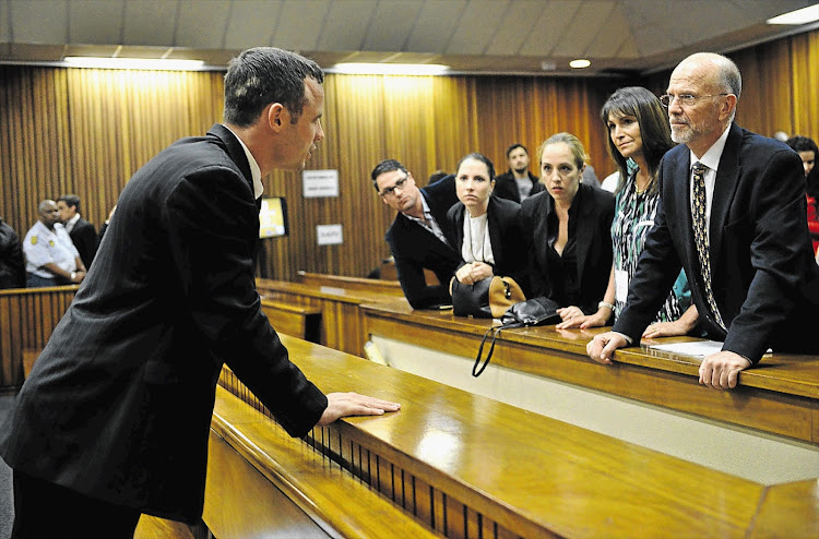 Oscar Pistorius talking to family members during a break in his murder trial. Those in the picture include his brother Carl, far left, his sister Aimee, next to Carl, and his uncle Arnold, on the right. File photo.