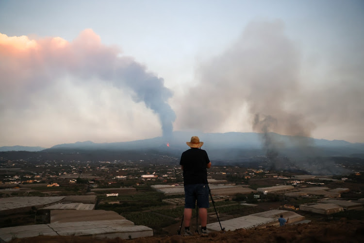 A man looks as lava and smoke rise following the eruption of a volcano on the Canary Island of La Palma, in La Todoque, Spain, September 26, 2021.