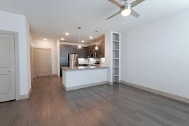 Kitchen with dark cabinets, stainless steel appliances, granite countertops, wood floors into living room with built in shelves