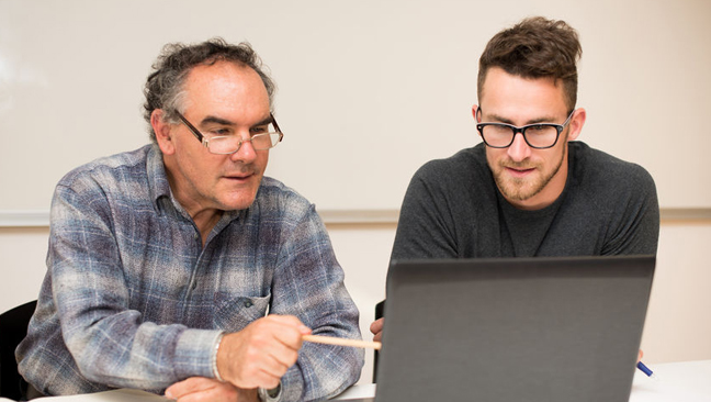 Mentor and mentee having a conversation looking at a laptop