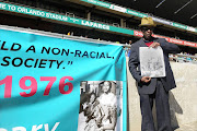 A file picture of former student leader Edwin Siwedi holds up his picture taken on 16 June 1976 as a 19 year old student marching down the street against the apartheid regime.