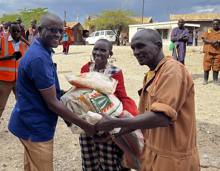 Senior chief Joel Saiyanks on the left helps in food distribution in Namanga on Friday.